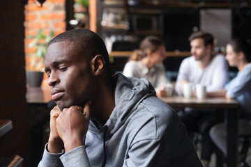Sad african guy feel lonely sitting alone in cafe
