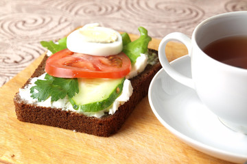 sandwiches with cottage cheese sour cream cheese greens vegetables and a Cup of tea with rose hips