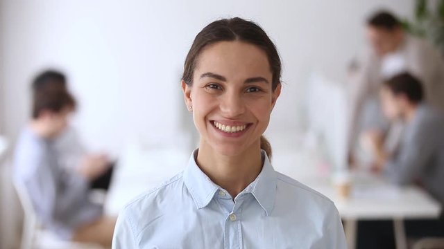 Video portrait of smiling millennial female employee intern in office
