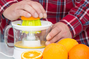 man making orange juice with juicer