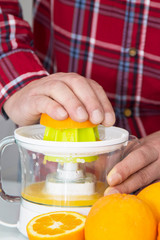 man making orange juice with juicer
