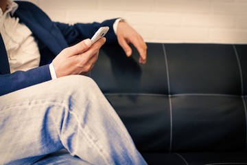 businessman sitting on the couch with mobile phone