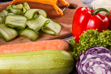 young woman in a gray apron cuts a cucumber