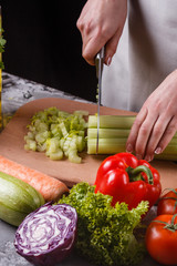 young woman in a gray apron cuts a celery