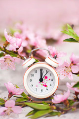 Spring blossom concept. Miniature clock, flowering tree close-up and copy space. Pink natural texture of natural flowering tree.