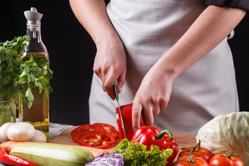 young woman slicing peppers in a gray apron