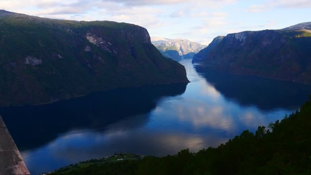 Clouds moving over fjord Aurlandsfjord and summer mountains. Norwegian landscape from Stegastein viewpoint. National tourist route Aurlandsfjellet. Time lapse