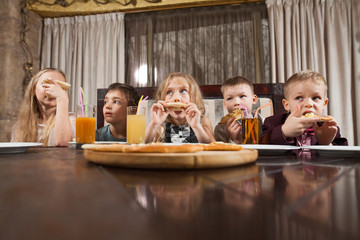 children eat pizza in a restaurant.