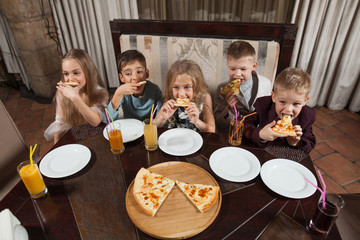 children eat pizza in a restaurant.