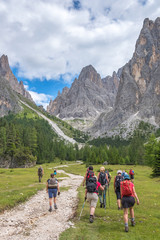 People are walking on a hiking trail to the mountains in a beautiful alpine landscape
