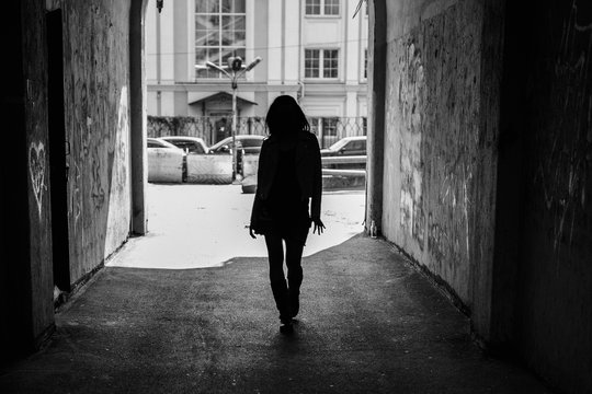 Black and white photo, silhouette of a girl in the architectural arch of the tunnel