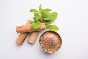 Chandan or sandalwood powder with sticks and green leaves
