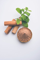Chandan or sandalwood powder with sticks and green leaves