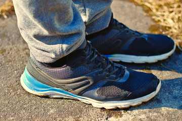 Legs in gray sweatpants and black running shoes sneakers with white and blue soles on the asphalt concept for healthy and active sport lifestyles