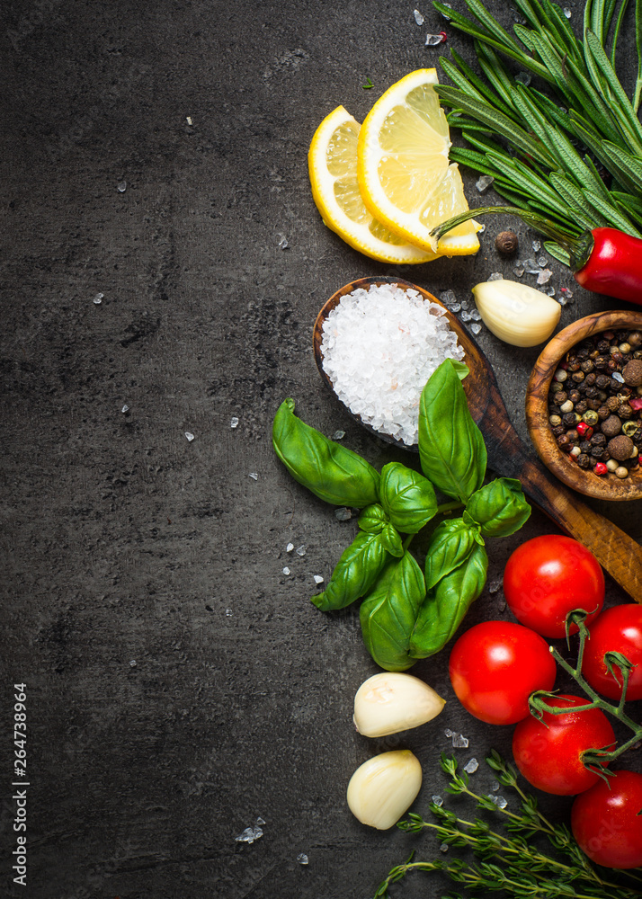 Wall mural Selection of spices and herbs on dark stone table.