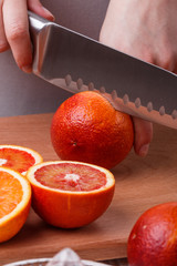 young woman in a gray apron cuts blood orange