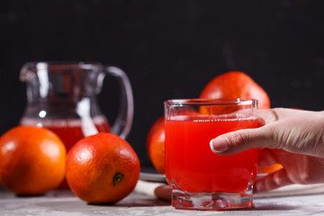 young woman in a gray apron takes a glass of juice blood orange