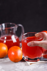 young woman in a gray apron takes a glass of juice blood orange