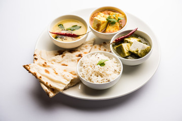 Obraz na płótnie Canvas Indian vegetarian platter / Thali having Palak paneer butter masala, dal makhani, flat bread or naan and rice served in a white plate