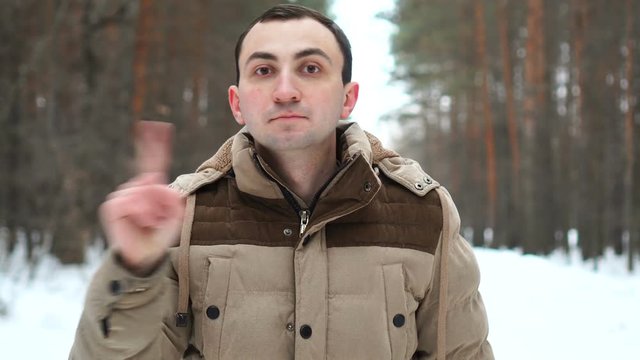No, Young Man Rejecting Offer by Waving Finger Against Backdrop of Winter Forest