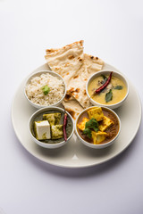 Indian vegetarian  platter / Thali having Palak paneer butter masala, dal makhani, flat bread or naan and rice served in a white plate