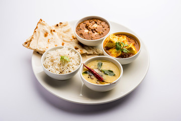 Indian vegetarian  platter / Thali having Palak paneer butter masala, dal makhani, flat bread or naan and rice served in a white plate