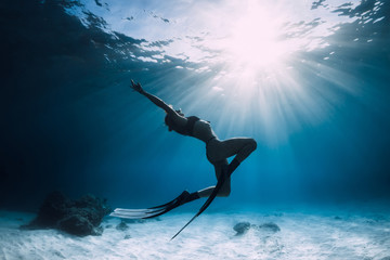 Woman freediver over sandy sea with fins. Freediving in ocean