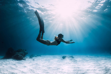 Woman freediver over sandy sea with fins. Freediving in ocean