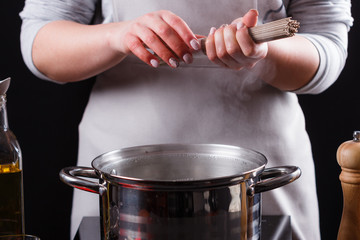 young woman in a gray aprons is preparing a noodle soba