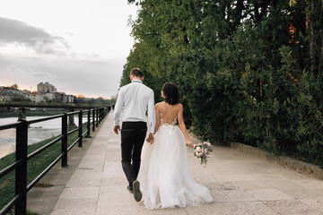 happy bride and groom walking along the promenade at sunrise. Wedding in Amsterdam