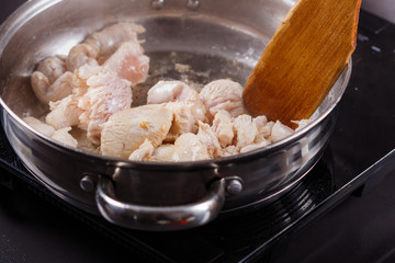 young woman in a gray aprons roasts chicken fillet with carrots