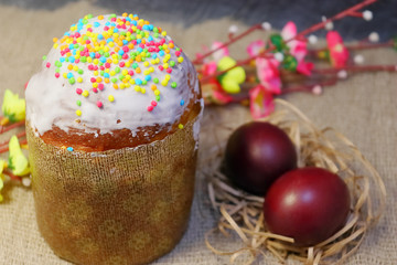 Easter cake in white glaze and sprinkling of colored sweet balls. Painted Easter eggs.