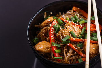 Buckwheat noodle in a black bowl on chicken fillet
