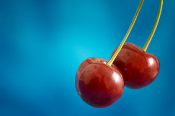 two red cherry cherries fruit over blue background in artistic dreamy style 