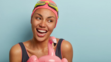Sportswoman attends sports section, looks away with broad smile, has white teeth. Attractive woman...