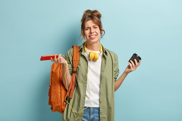 Hopeless dissatisfied woman looks with apathy at camera, upset with softwre problem on mobile phone...