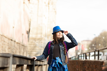 Young stylish woman walking on the old town street, travel with backpack and blue hat. Ukraine, Lviv