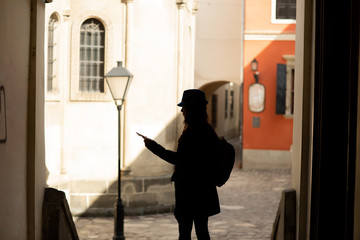 Young stylish woman walking on the old town street, travel with backpack and blue hat. Ukraine, Lviv