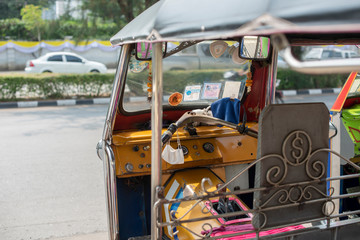 Fototapeta premium Well known and famous local taxi in Thailand, Tuk-Tuk, parking nearby tourist place, waiting for passengers asking for a ride. Image showing lots of details of colourful equipments and elements.