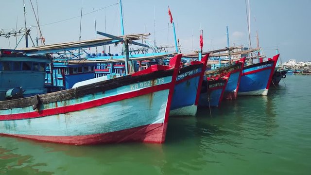 Aerial low sea water bow ships lot multicolored boats fishing old asia wooden style authentic doc harbor. Large marina parking. Fish catch industry profession. Vietnam Thailand. Sunny day. Drone