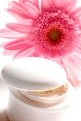 Fototapeta na wymiar white jar with cosmetics cream and pink gerbera daisy flower like wellness, beauty, spa, and body care, skinconcept 