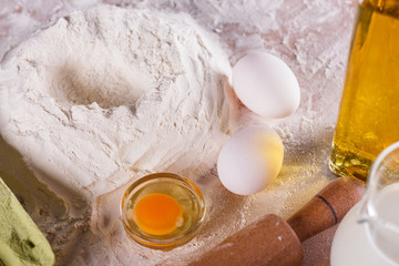 young woman in apron kneading dough on board
