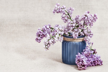 Spring flowers of lilac in vase on rustic tablecloth with copy space. Lilac closeup. Selective focus.