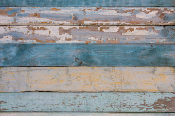 Old yellow blue white wooden wall fence of wooden boards with peeling paint. horizontal lines. rough surface texture