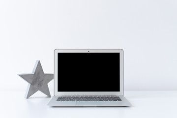 Open laptop and concrete grey star on the desk with white background