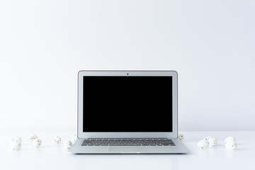 Fototapeta premium Open laptop and easter eggs on the desk with white background