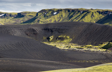 Dramatic iceland landscape with a green hill and black lava looks like a moon. Serenity of Iceland.