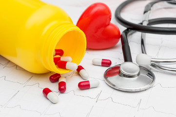 Pills, stethoscope and red heart on the cardiogram. Medical concept.