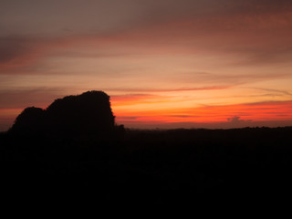 Silhouette mountain hill at sunrise sunset gold orange yellow sky and clouds.