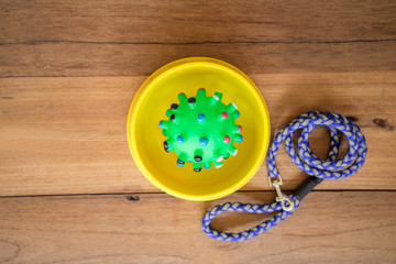 Rubber toy in bowl on wooden background.  Pet accessories concept